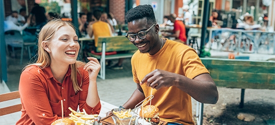 Friends having fun eating burgers and fries at an outdoor restaurant.
