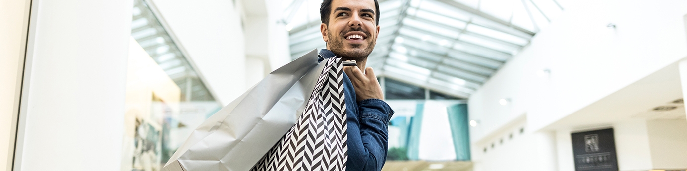 Man walking through a shopping mall with bags.