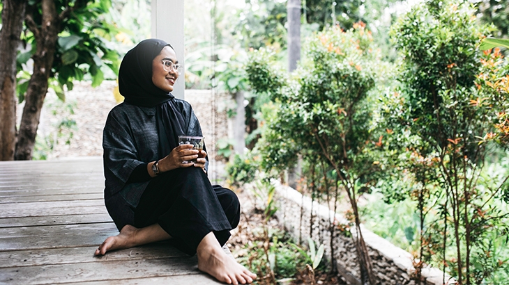 Young woman wearing hijab sitting in backyard.