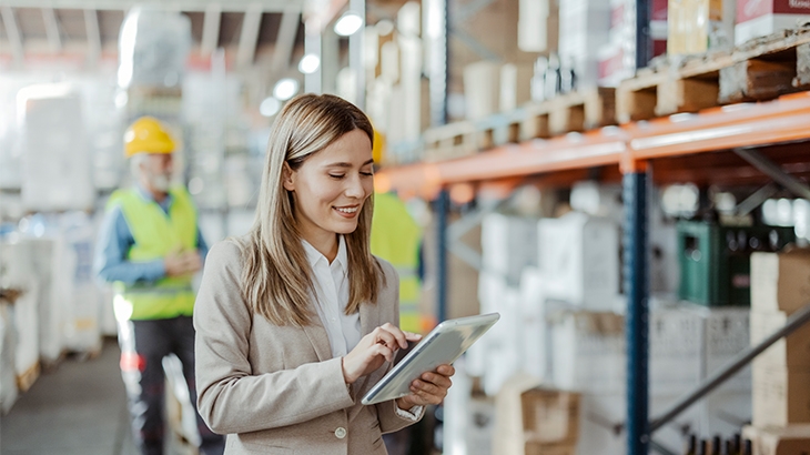 A businesswoman taking inventory in the warehouse on a tablet.