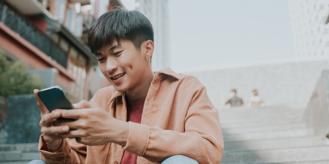 Man sitting on stairs outside using his smartphone.