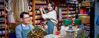 A man and woman working in a festive store that sells bright colorful gift wrapping supplies.