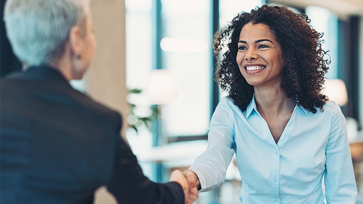 Businesswoman shaking hands with businessman across desk