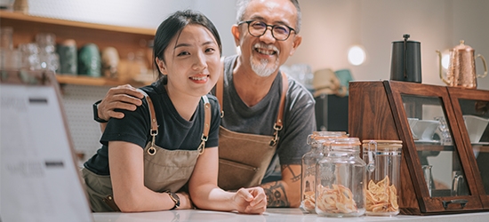 Father and daughter running their cafe, smiling at the counter. 
