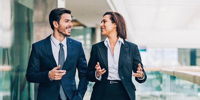 Two business people walking and talking in an office building.