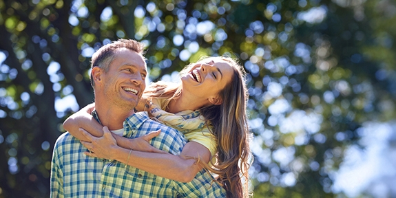 Couple laughing outside on a summer day.