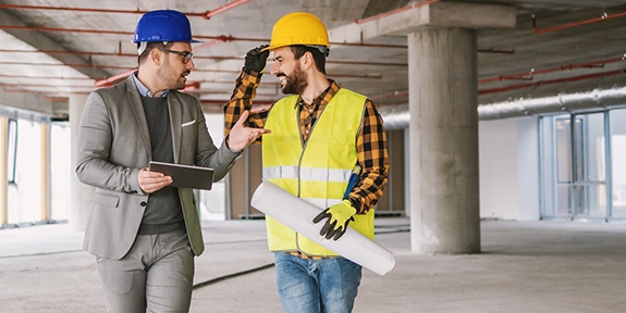 Construction worker and architect talking in building under construction.