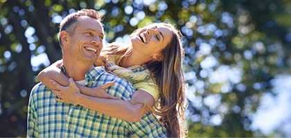 Couple laughing outside on a summer day.