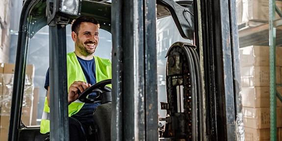 Warehouse worker driving a forklift in a storage room.