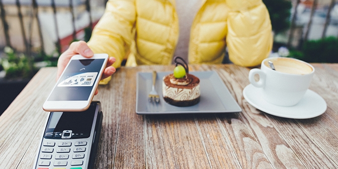 Woman paying for dessert with digital debit card mobile pay.