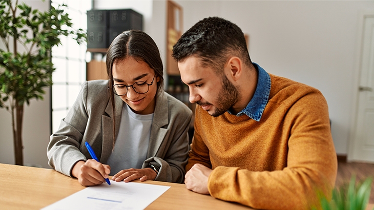 Young couple signing closing paperwork