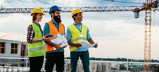 Engineer, architect, and contractor on the construction site with a crane in the background.