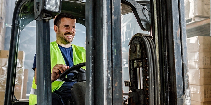 Warehouse worker driving a forklift in a storage room.
