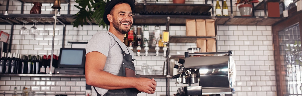 Happy young bar owner standing at the counter.