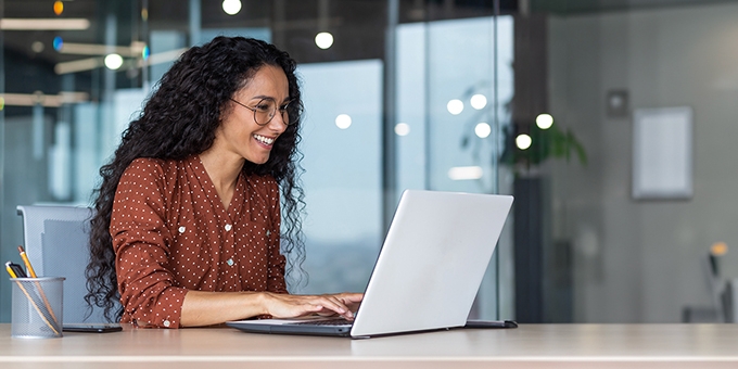 Happy businesswoman in an office working on a laptop.