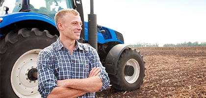 Farmer standing in front of a tractor.