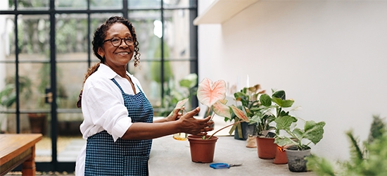 A woman smiling while potting a plant in her shop.
