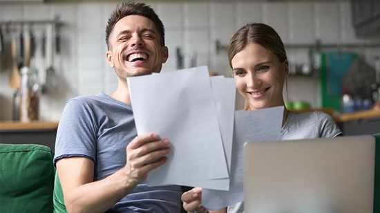 Una pareja riendo mientras revisa sus finanzas.