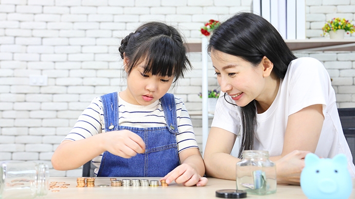 Mother teaching daughter about saving money with coins