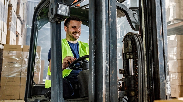 Warehouse worker driving a forklift in a storage room.