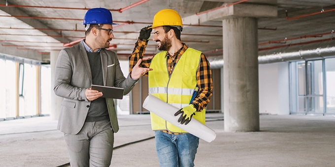 Construction worker and architect talking in building under construction.