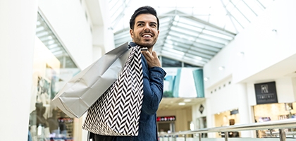 Man walking through a shopping mall with bags.