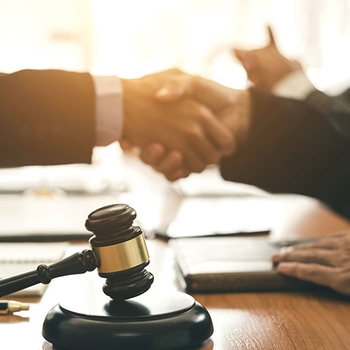 Closeup of businessmen shaking hands over desk at law firm