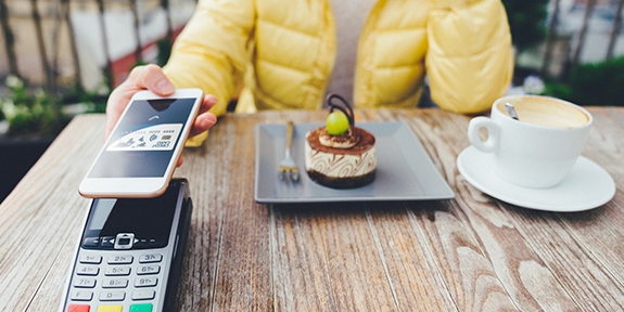 Woman paying for dessert with digital debit card mobile pay.