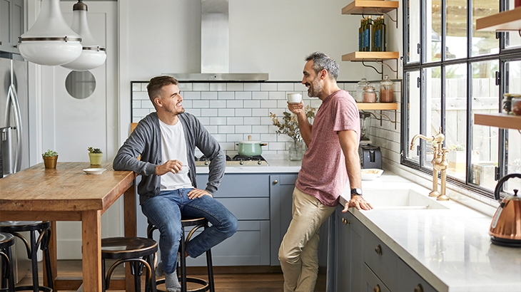 Two men standing in a beautiful modern kitchen having coffee.