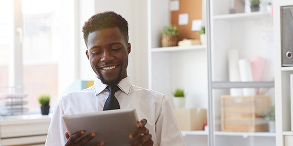 Young businessman with tablet sitting at desk in office.