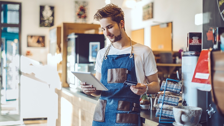 Young business owner in shop learning how to qualify and apply for small business credit card.