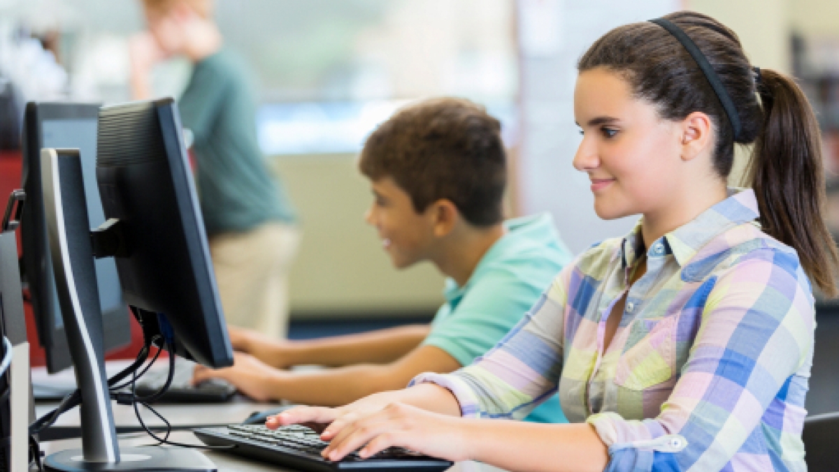 Happy female teenager using a computer in the computer lab
