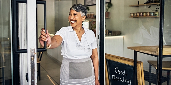 Smiling cafe owner opening her shop for the morning.