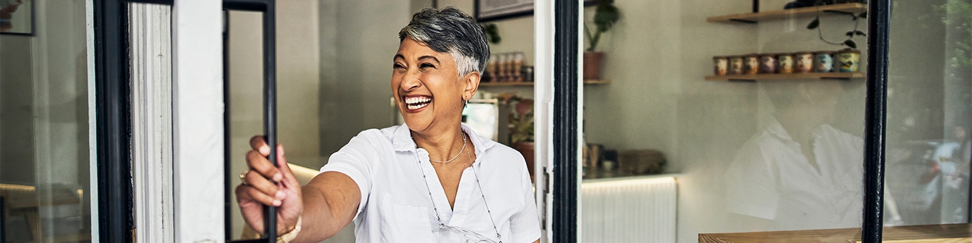 Smiling cafe owner opening her shop for the morning.