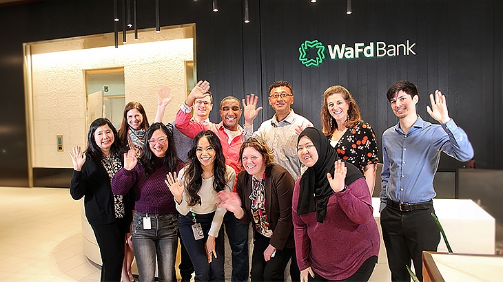WaFd employees waving as a group in a WaFd Bank lobby