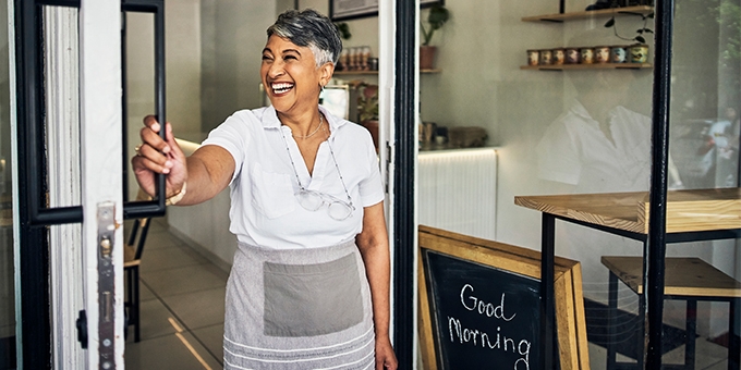 Smiling cafe owner opening her shop for the morning.