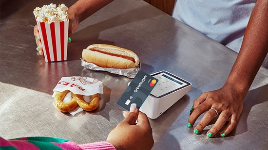 A customer is using a Greenlight card to pay for snacks at a counter with a point-of-sale machine.