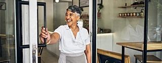 Smiling cafe owner opening her shop for the morning.