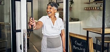 Smiling cafe owner opening her shop for the morning.