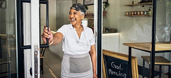 Smiling cafe owner opening her shop for the morning.