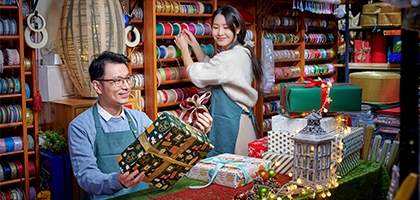 A man and woman working in a festive store that sells bright colorful gift wrapping supplies.