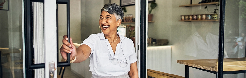 Smiling cafe owner opening her shop for the morning.